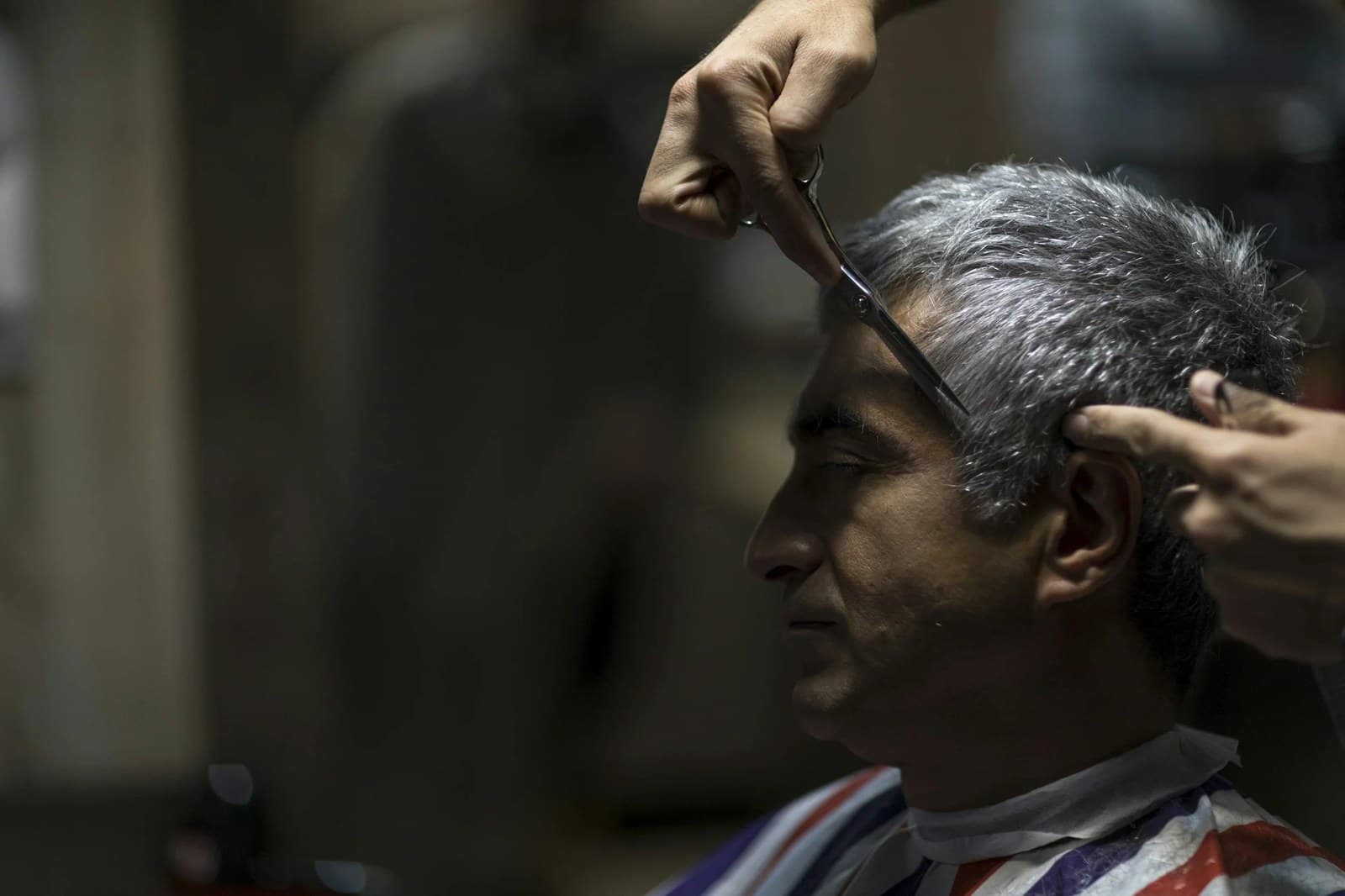 A barber giving a gentle, patient haircut to an elderly client